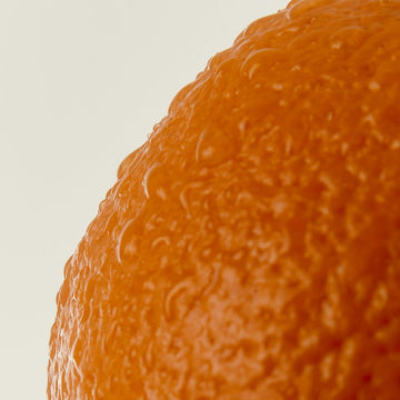 Close-up of an orange with a textured surface on a light background