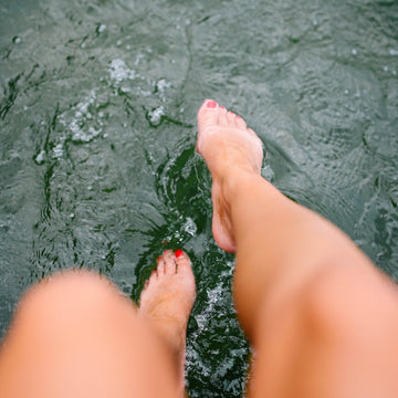 Feet with red nail polish standing in water