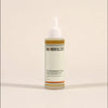 Bottle of 'The Herbalist's Elixir' by Frondescent on a beige background. Designed to give your hair the nutrients it needs. All natural ingredients.