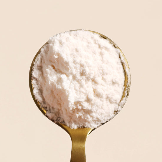 Gold spoon filled with Inositol powder from Frondescent's Perfect Ratio Inositol supplement on a beige background. Helps regulate hormones, blood sugar, boost energy and hair growth, and help with insulin resistance.