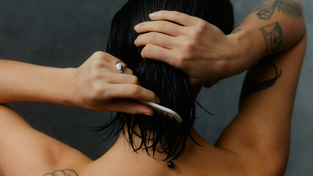Person combing their wet hair against a dark background